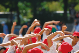 紅の紅白帽子をかぶった子供たちが元気よくラジオ体操をする様子の写真